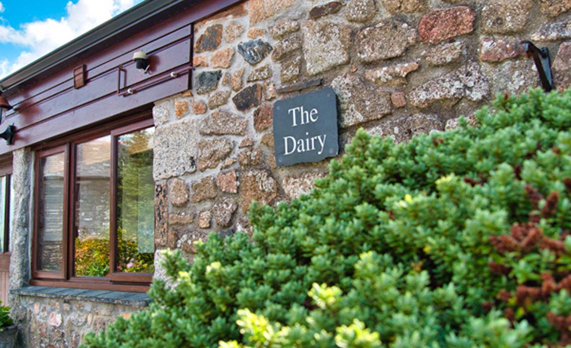 A photo of a slate sign on the outside of a stone house that reads "The Dairy"