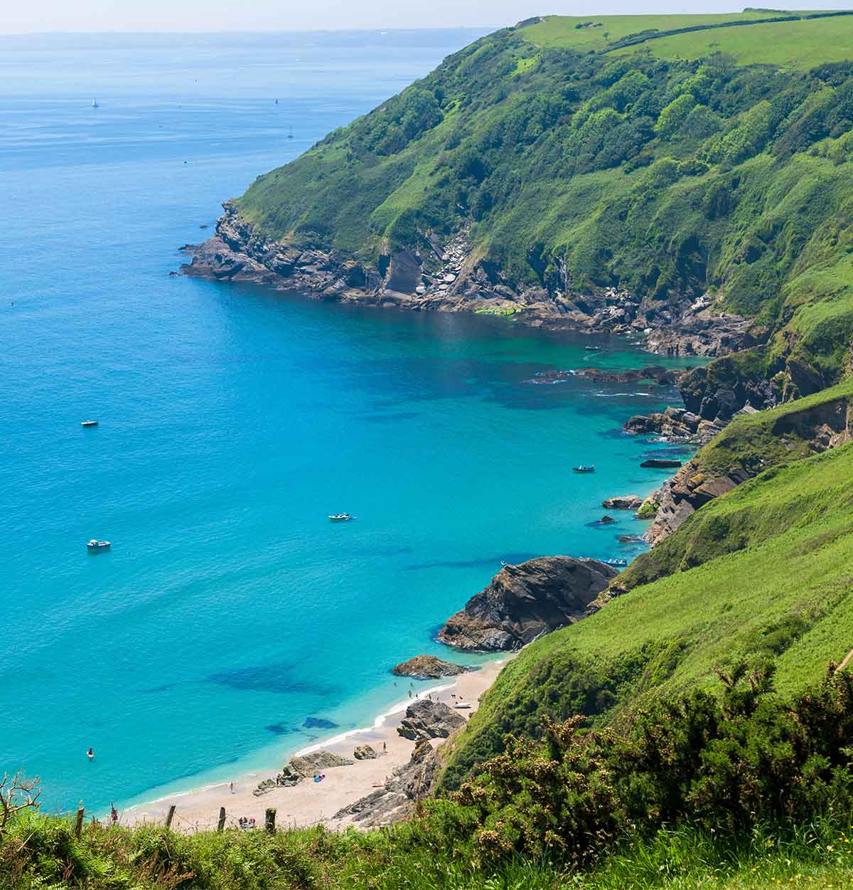 Lush green cliffs and bright blue sea on the coastline of Cornwall